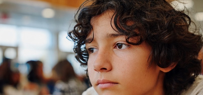 Teen sitting withdrawn in a school cafeteria