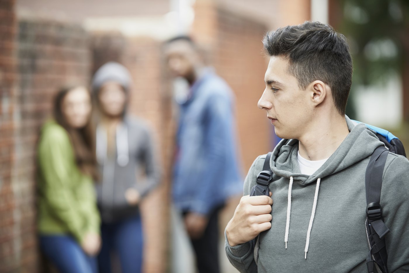 Teen boy walking away from a group of peers