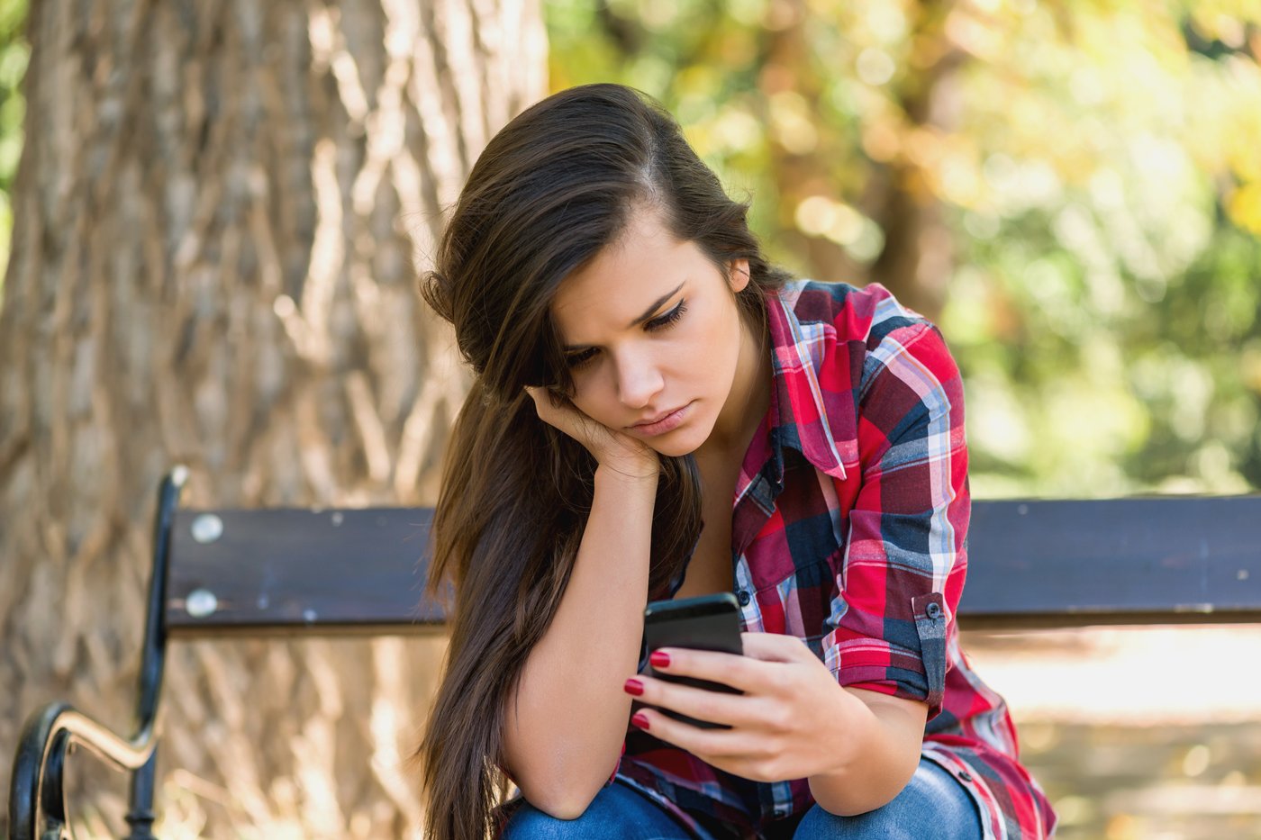 Teen looking down at her phone on a bench